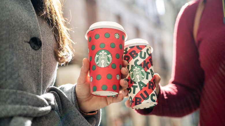 hands holding Starbucks holiday drinks