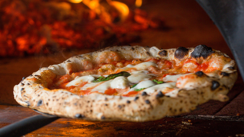 Margherita pizza being removed from pizza oven