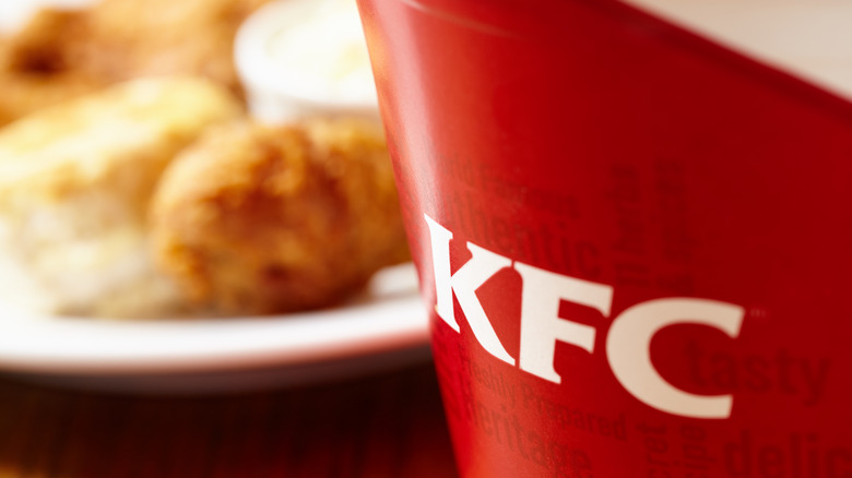 KFC bucket with food in background