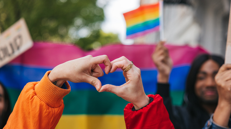 hands forming heart over pride flag