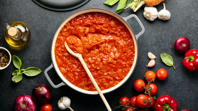 tomato sauce in saucepan surrounded by ingredients
