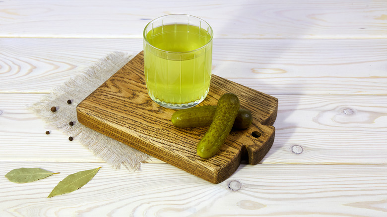 Glass of pickle juice on wooden board