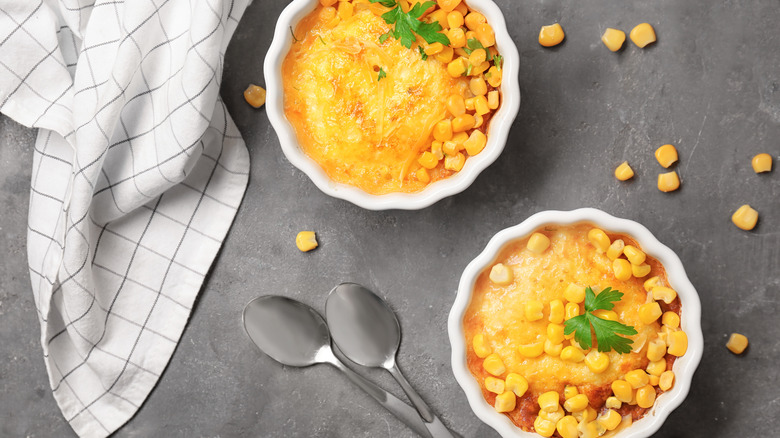 Corn casseroles in ramekins with spoons and napkins