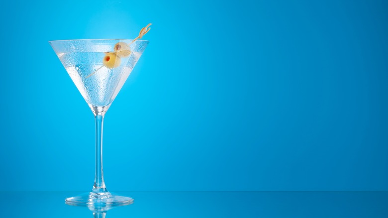 Martini with olives against blue background 