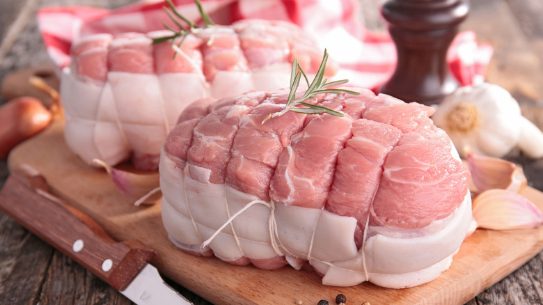 Raw trussed pork butt with garlic, herbs and onion