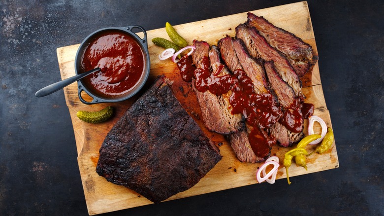 Sliced brisket on a cutting board with sauce