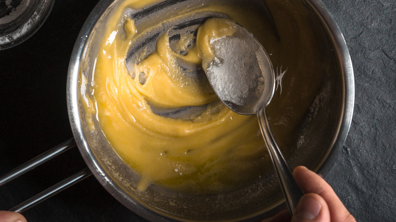 Hands making roux in pot.
