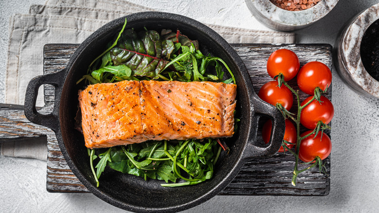 Cooked salmon over greens in skillet