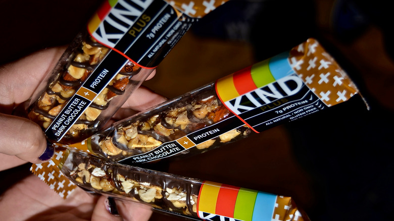 A person holds three KIND bars