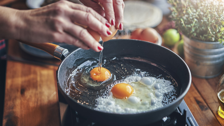 cracking eggs into frying pan