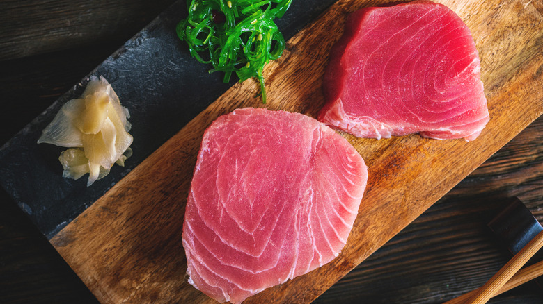 Raw tuna steaks on wooden board