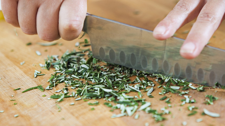 hands chopping herbs with knife 