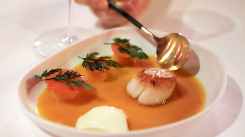 Michelin dish scallop in sauce being eaten