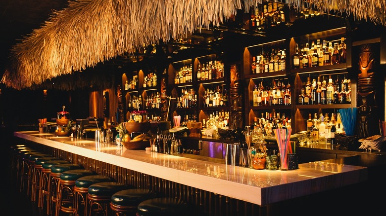 Dark, warmly-lit tiki bar with thatched roof