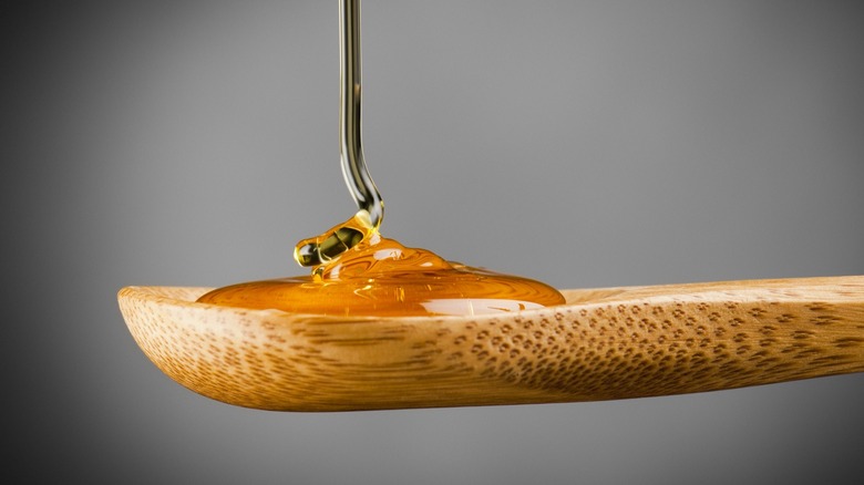 Honey being drizzled onto wooden spoon