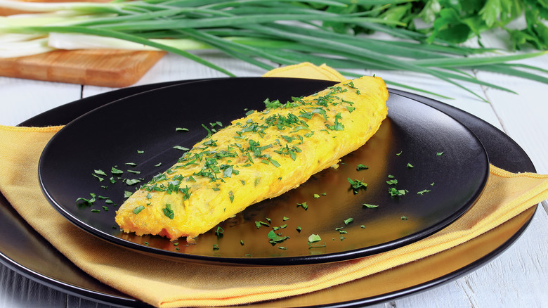 Fluffy omelette with herbs on a black plate