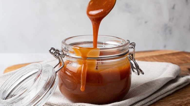 Spooning homemade caramel sauce out of jar