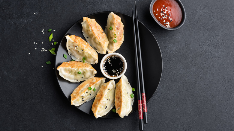 Jiaozi on a plate with soy sauce in a dish and chopsticks