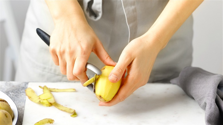 Hands peeling potato 