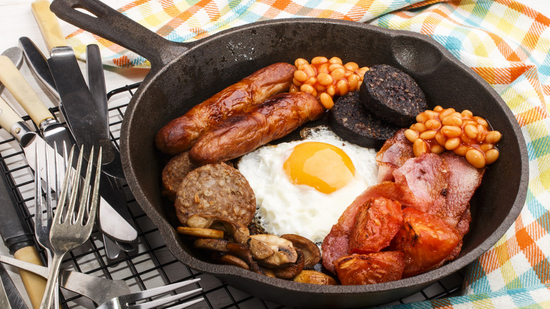 Irish breakfast in pan with silverware on plaid tablecloth