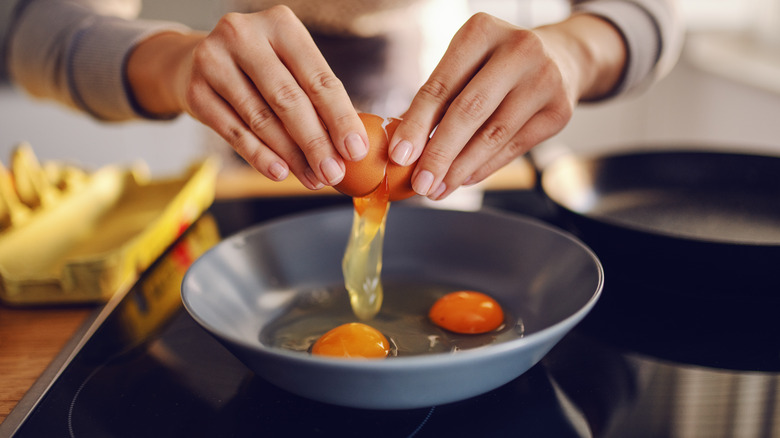 Woman cracking eggs into pan