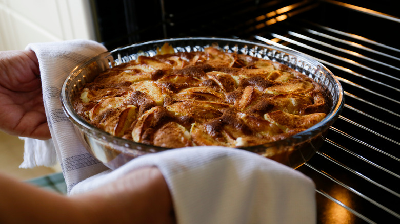 Hands pie an apple crisp out of the oven