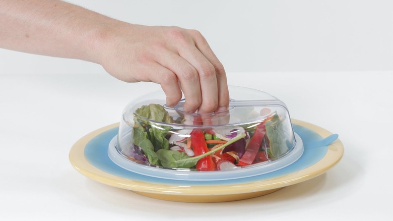 hand placing PlateTopper on salad