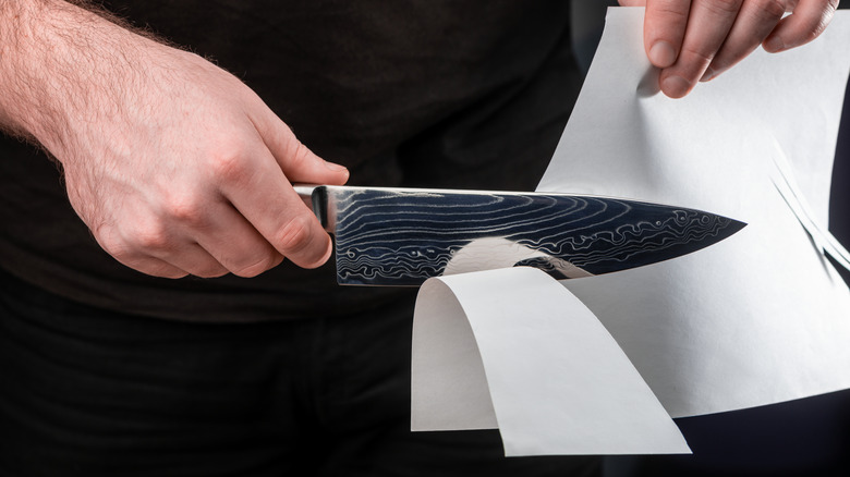 Knife slicing through paper