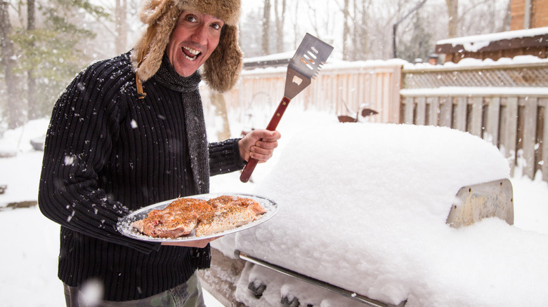 Person cooking on snow-covered grill