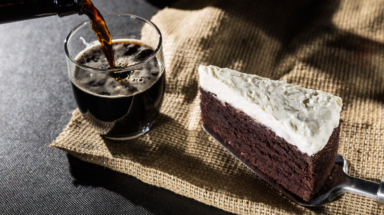 Pouring a glass of dark beer with a slice of dark cake with white frosting