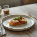 Elegant burrata prosciutto crostini appetizer arranged on a table with fresh basil leaves
