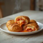Easy homemade pizza rolls with melted cheese and pepperoni on a serving platter, perfect for parties.