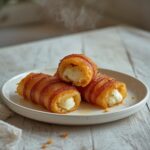 Crispy bacon-wrapped mozzarella sticks on a plate, golden and ready to eat