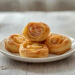 ham and cheese pinwheels: : Golden ham and cheese pinwheels on a baking sheet with flaky crescent dough