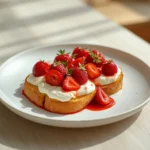 roasted strawberry whipped ricotta toast: : Roasted strawberry whipped ricotta toast on a plate with creamy topping and sweet berries.