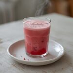 A vibrant pink raspberry colada twist drink in a glass with tropical garnish on a table.