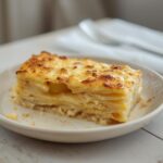 A golden baked dish of roasted garlic potatoes au gratin with bubbly cheese on top.