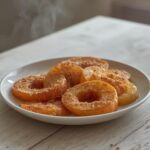 Golden crispy air fryer apple fries on a plate, sprinkled with cinnamon sugar, ready to eat.