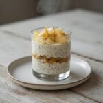A creamy apple chia pudding served in a glass bowl, showing the layered texture with visible chia seeds and apple pieces.
