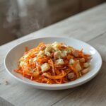 A beautiful bowl of carrot apple salad with grated carrots and apple chunks, showcasing a vibrant orange and green color palette.