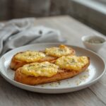 A golden-brown cheesy garlic bread recipe on a table, melted cheese bubbling over buttery garlic topping.