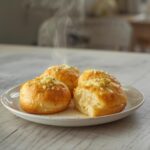 Golden cheesy garlic rolls arranged on a table, showing a soft, buttery texture and melted cheese.