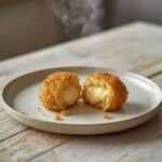 Golden crispy potato cheese balls on a serving platter, perfect party snack with melty cheese filling.