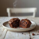 Freshly baked double chocolate chip muffins with melted chocolate chunks on a plate.