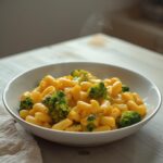 A creamy bowl of healthy one pot broccoli mac and cheese, showing tender pasta and green broccoli florets in a rich cheese sauce.