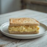 A complete Japanese egg sandwich served on a plate with fluffy milk bread and creamy egg salad visible.