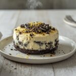 Oreo no bake cheesecake cups topped with lemon zest in serving glasses on a table
