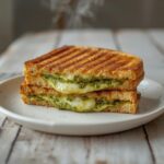 A golden, crispy pesto grilled cheese sandwich served on a plate, perfect for a quick lunch or cozy dinner.