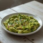 A vibrant bowl of restaurant-worthy guacamole with visible chunks of avocado, cilantro, and red onion.