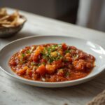 Fresh roasted salsa in a bowl with a vibrant red and green color, topped with chopped cilantro, served with tortilla chips for dipping.